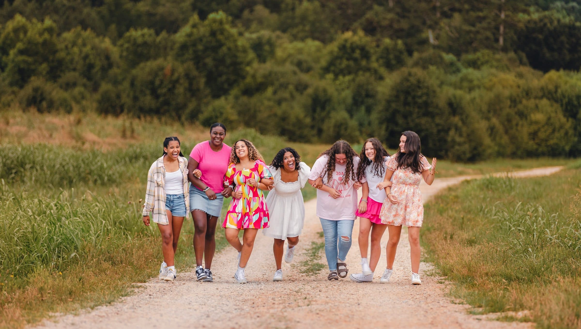 A group of friends walking together on a sunlit path, laughing